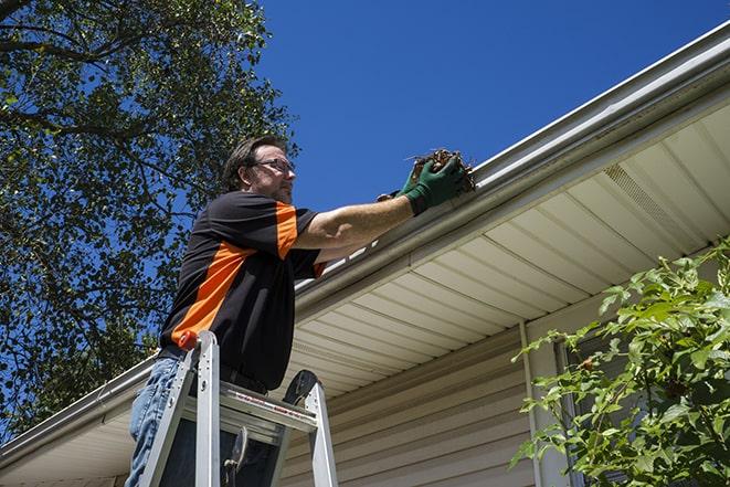 a repairman working on a broken gutter system in Bingham Farms